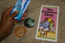 a hand holding a Condom Quiz brochure next to two condom wrappers