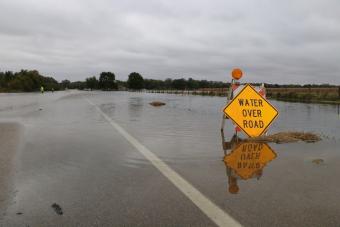 Flooded roadway with sign reading "Water Over Road".