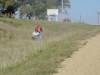 Cleanup volunteer in the ditch along the road.