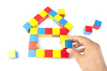 wooden blocks (yellow, blue, red, orange) being built into a house