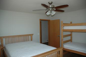 A bedroom at Summit Cabin with a queen bed and twin bunk beds.