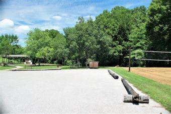 View of picnic shelter, large parking area and sand volleyball court.